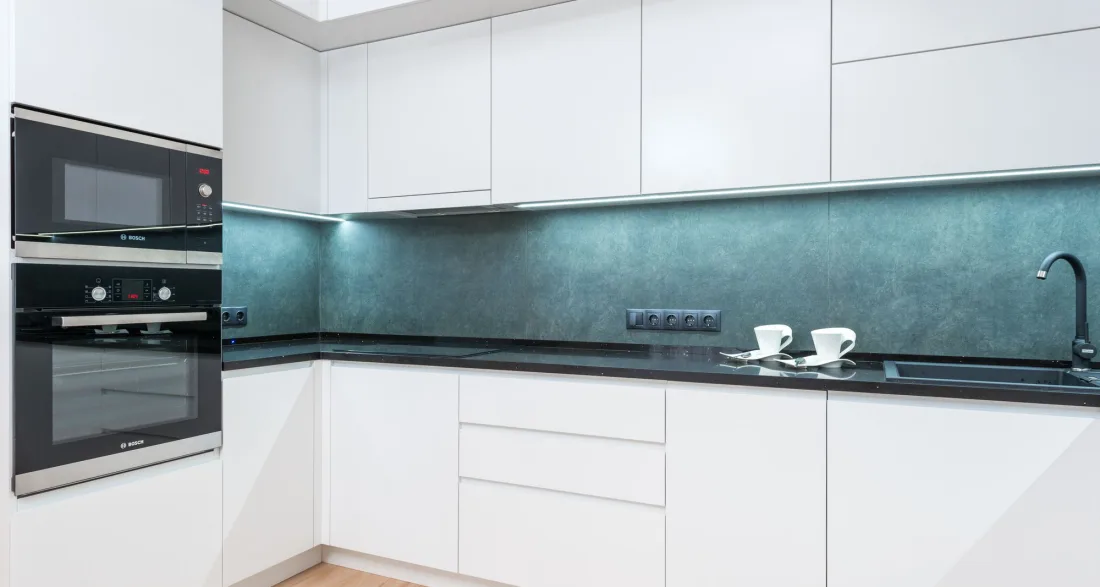 White fitted kitchen with a built-in wall oven beside the worktop