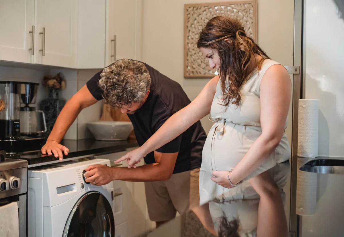 A couple looking over the controls of a front load washing machine at home