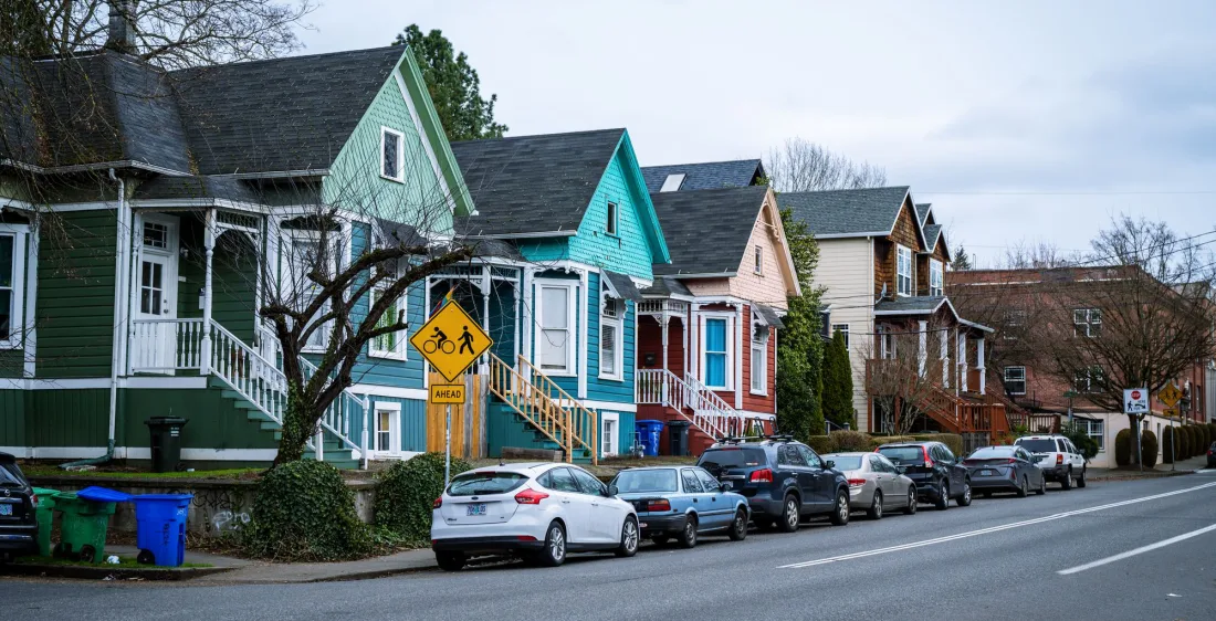 A street of tall painted family houses running downhill on a bright day