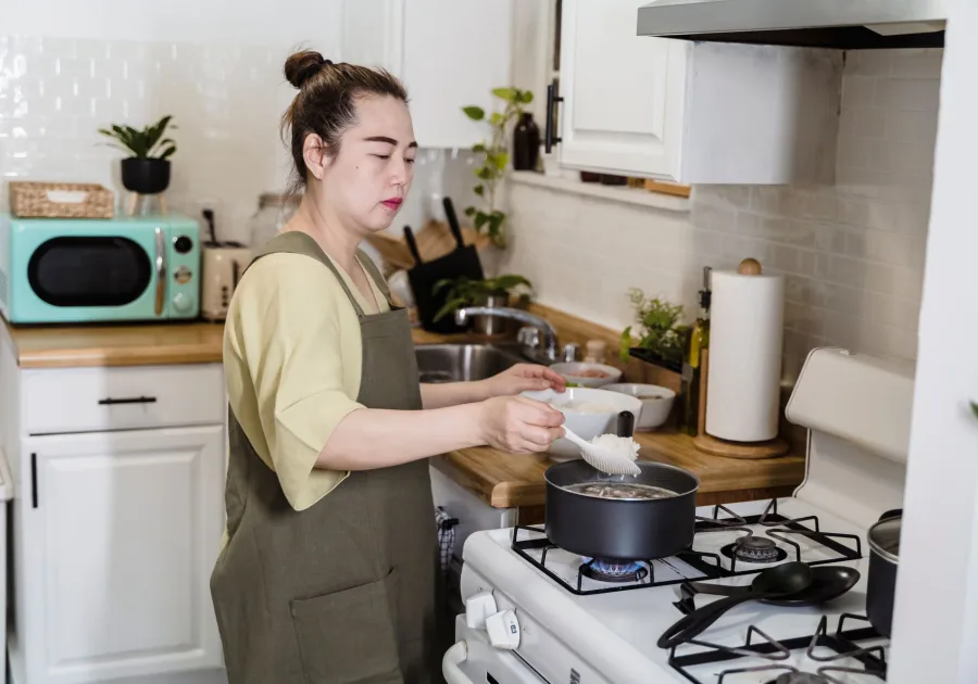 A pan heating on a gas hob while somebody cooks at the range