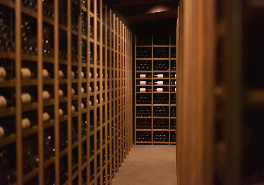 Wine bottles resting on floor to ceiling wooden racks in a cellar